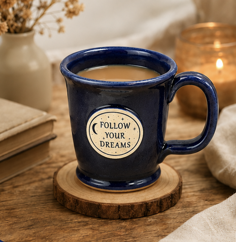Follow Your Dreams navy stoneware mug resting on a wood coaster